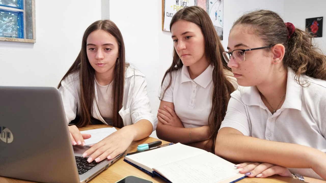 Eine Frau erklärt zwei anderen Frauen etwas am Laptop