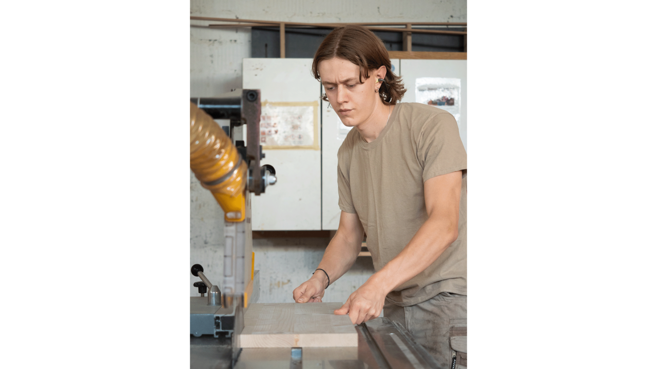 Ein konzentrierter Mann zersägt mit einer grossen Maschine ein Holzbrett