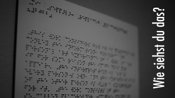 Eine mit Braille-Text beschriftete Metallplatte. Der Text beschreibt ein Objekt in einem finnischen Museum und hat mit dem darunterstehenden Beitrag nichts weiter zu tun. Er dient als Bindeglied für sehende Personen, damit sie einordnen können, um welches Thema es ungefähr gehen wird. Rechts steht in senkrechter Schrift der Beitragstitel "Wie siehst du das?".